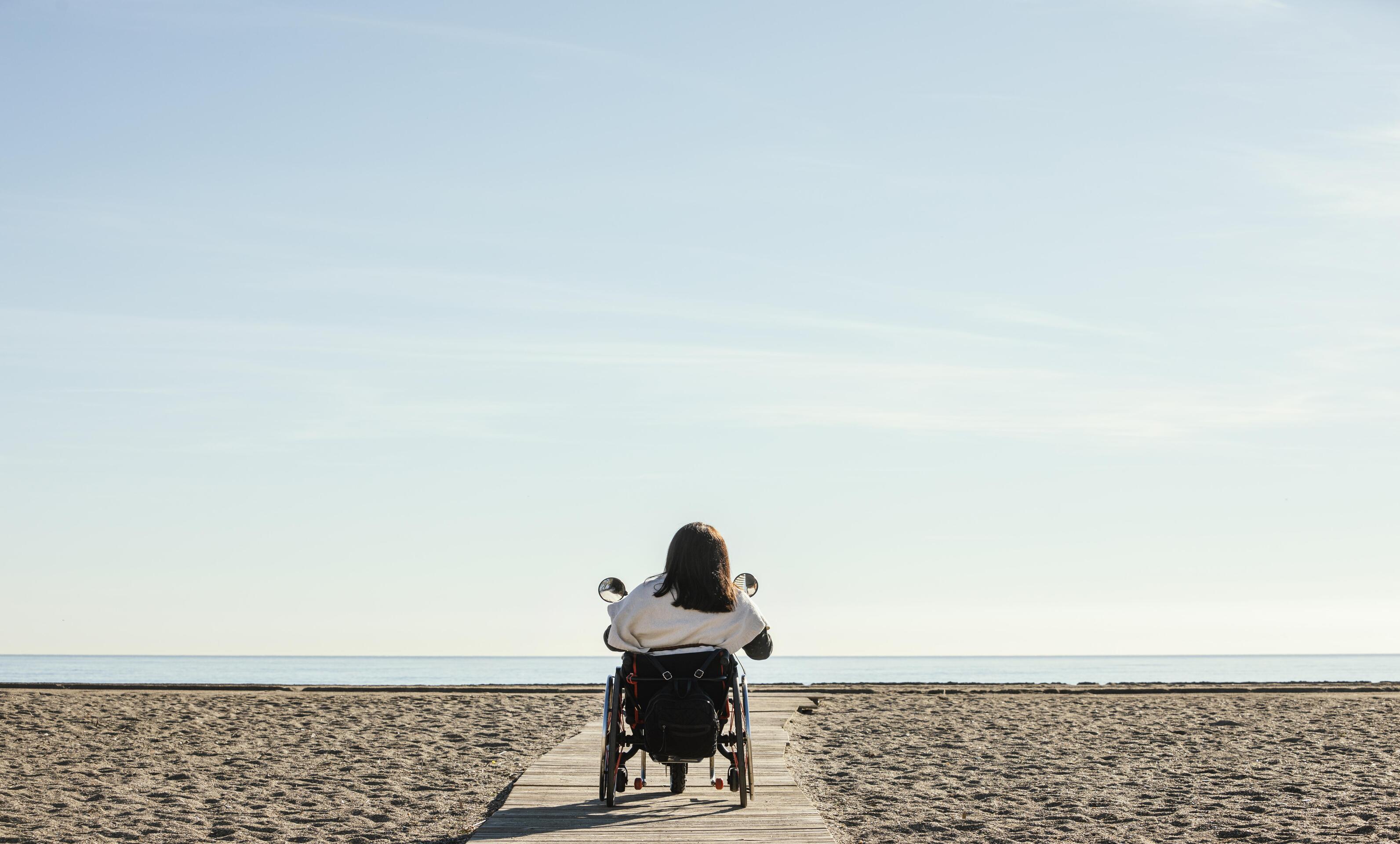 vista posterior mujer silla ruedas playa 